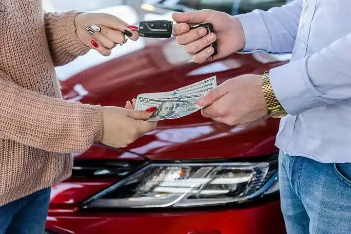 two people handing over cash to buy a car